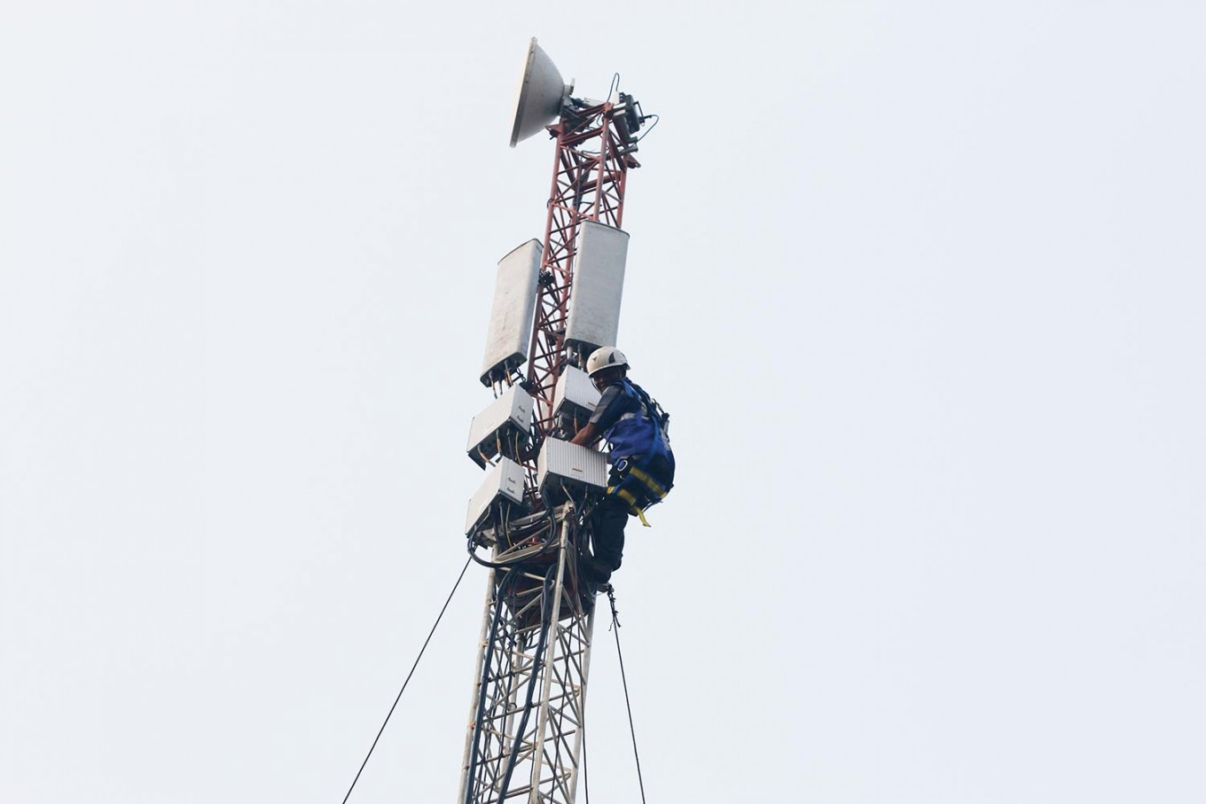 A technician inspects a base transceiver station (BTS) on a telecommunications tower at the Tangerang-Merak toll road in Banten, West Java, on June 6, 2018.