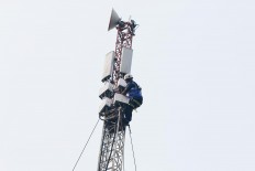 A technician inspects a base transceiver station (BTS) on a telecommunications tower at the Tangerang-Merak toll road in Banten, West Java, on June 6, 2018.