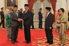 Indonesia's largest Islamic organization Nahdlatul Ulama (NU) executive Yahya Cholil Staquf (left) shakes hand with President Joko 