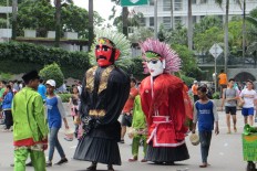 A couple of giant effigies 'Ondel-ondel' walk down the street of Jenderal Sudirman in South Jakarta. 