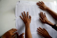 Polling station officials put up the eligible voter list in Kampung Gaga in Larangan, Tangerang regency, Banten, on June 26, 2018.