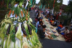 Standing tall: Just beside the feasting villagers is a rice cake offering known as gunungan ketupat. JP/Maksum Nur Fauzan