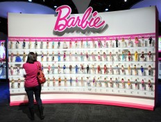 In this file photo taken on February 14, 2010 a woman photographs a wall of Barbie dolls in the Mattel display at the annual Toy Fair in New York. 'Robotics Engineer Barbie', an inspirational new version of Barbie, will encourage young girls to embark on careers in engineering and the sciences, the iconic doll's manufacturer Mattel said on June 26, 2018.