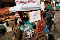 An official drives a voter back home in a pedicab after she cast her vote in Cibadak subdistrict, Astana Anyar district, Bandung on Wednesday, June 27, 2018. The neighborhood unit officials in the subdistrict hired pedicab drivers to pick up and take home elderly voters so they could cast their votes. JP/Arya Dipa