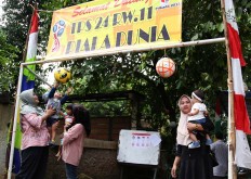 Three young mothers hold their babies at the entrance to a World Cup-themed polling station in Tapos, Depok, West Java. on Wednesday, June 27, 2018. JP/P.J. Leo
