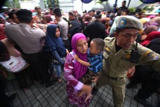 A public order officer escorts a mother and son to a safer place after being squeezed in the line. JP/Boy T. Harjanto