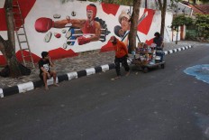 Artists pull a cart loaded with paint to continue working on their murals. JP/Maksum Nur Fauzan