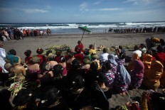 People pray on the beach before proceeding with the ceremony. JP/Boy T. Harjanto