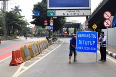 Officials put up a sign that bars vehicles from entering the Slipi 1 tollgate in West Jakarta. 