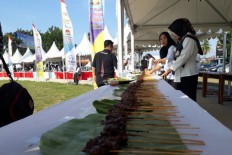 Participants grill skewers of octopus satay at Sunday's Octopus Satay Festival in Kaur, Bengkulu. The festival has made a national record as the largest octopus culinary festival.