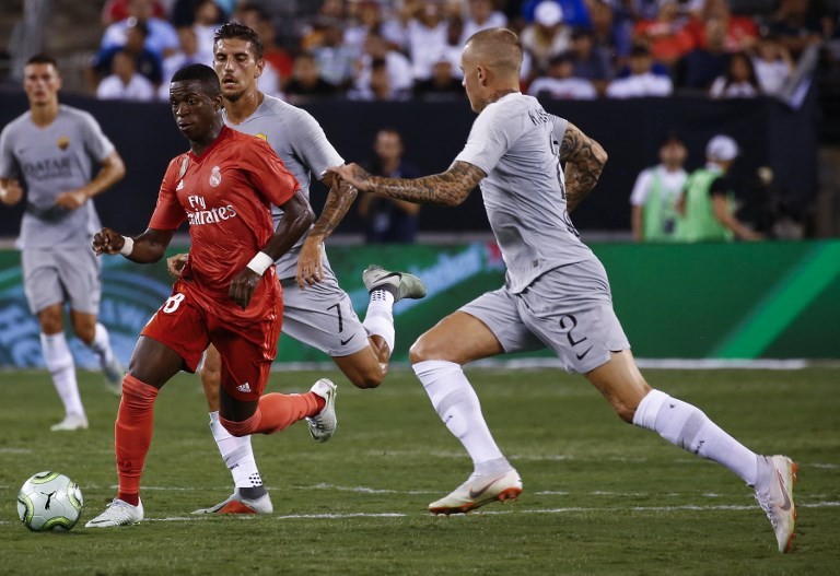 EAST RUTHERFORD, NJ - AUGUST 7: Vinicius Junior #28 of Real Madrid drives between Lorenzo Pellegrini #7 and Rick Karsdorp #2 of Roma during their match at MetLife Stadium on August 7, 2018 in East Rutherford, New Jersey. Jeff Zelevansky/Getty Images/AFP 
