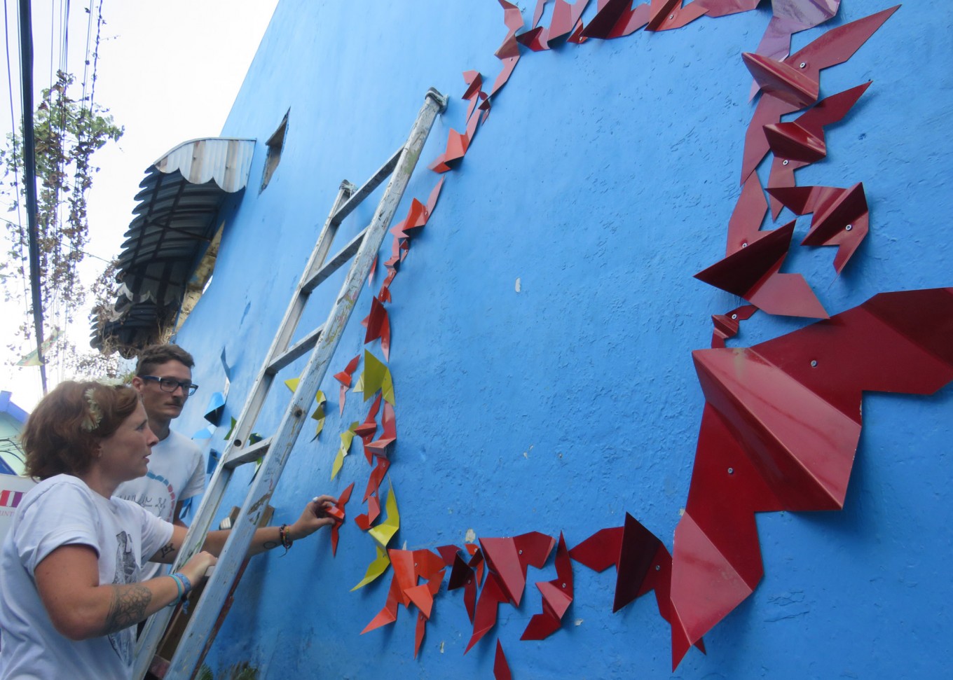 French artist Mademoiselle Maurice and her husband, Snez, decorate the blue walls of Kampung Biru Arema, Malang, East Java, with origami-shaped metal plates.
