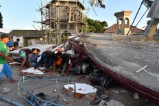 Residents and a search and rescue team member look under the ruins of a mosque in Pemenang, North Lombok, on Aug. 6, 2018, the day after a 6.9-magnitude earthquake struck the area. AFP/Adek Berry