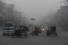 Residents use a road in Dumai city, Riau amid a thick smokey haze that blankets the city on Aug. 16, 2018. The smoke starts to fill the air as more hot spots are detected in the dry season. 