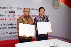 Protecting workers: Workers Social Security Agency (BPJS Ketenagakerjaan) president director Agus Susanto (left) and Law and Human Rights Ministry director general of immigration Ronny F. Sampie show cooperation agreement documents on the use of immigration data for a workers social security program.
