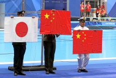 Officials hold the national flags of winning countries after they fell to the floor because of trouble with the flag pole. JP/Seto Wardhana
