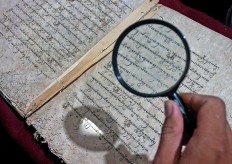 Glimpse of the past: A reader uses a magnifying glass to read an ancient manuscript from Yayasan Sastra Lestari’s (Yasri) collection.