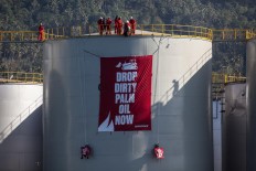 Greenpeace activists unfurl a banner reading "Drop Dirty Palm Oil Now" at a Wilmar International palm oil refinery in Bitung, North Sulawesi, in September. 