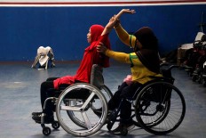 An athlete stretches, helped by her teammate, before the start of a training session. JP/Maksum Nur Fauzan