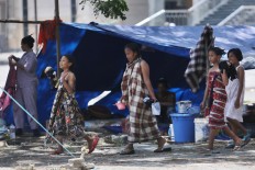 Girls walk past shelters after showering in the front yard of the Darussalam Grand Mosque in Palu on Friday, October 5, 2018. JP/Dhoni Setiawan