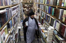 A Muslim religious man walks among books shelves at the Howeish book market in the holy city of Najaf, 150 kilometers south of Baghdad, on August 16, 2018. 