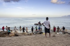 Fishermen and tourists gather on a beach near the town of Le Carbet of the French Caribbean island of Martinique to lift fishing nets at dawn on July 14, 2014. 
