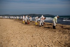Workers clean hydrocarbon slabs from oil spill from two ships that collided off the waters of Corsica, on Pampelone beach in Ramatuelle, in the Gulf of Saint-Tropez, southeastern France, on 18 October, 2018. 