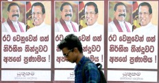Daily reminders: A man walks past a poster of Sri Lanka’s newly appointed Prime Minister Mahinda Rajapaksa and President Maithripala Sirisena on a main road in Colombo, Sri Lanka, on Sunday.