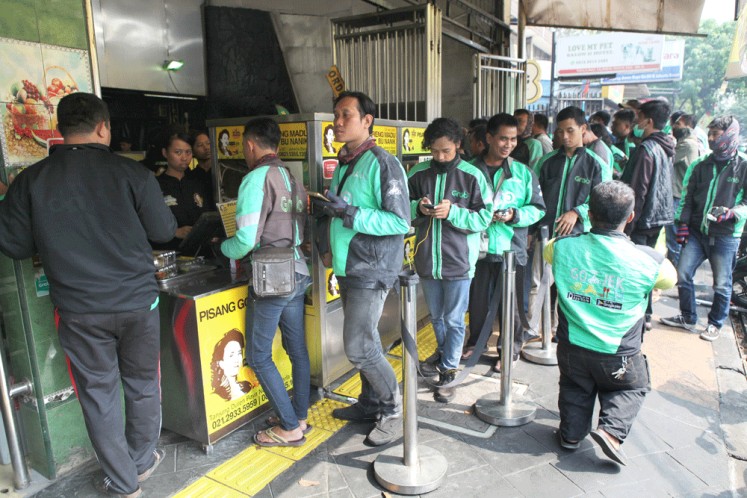 Wait for it: Ride-hailing app drivers queue up to buy food for their customers at the Pisang Goreng Madu Bu Nanik food outlet in Tanjung Duren, West Jakarta, in October 2019.