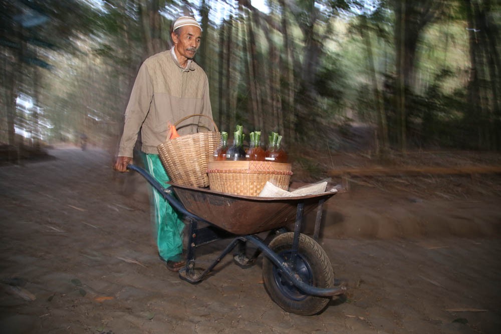 Seorang penjual bernama Kambali mendorong gerobak berisi jamu tradisional 