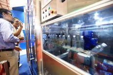 Visitors watch a demonstration of a bottling process at the Plastics and Rubber Indonesia 2018 Expo in Jakarta.