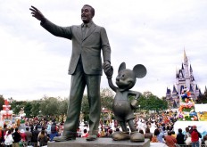 Walt Disney and Mickey Mouse statues stand at the Tokyo Disneyland in Urayasu city, suburban Tokyo while visitors enjoy Disney characters' parade on 13 November 2001.