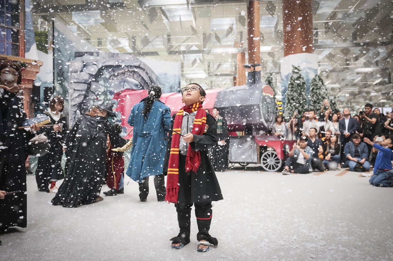 A young fan is enthralled by the snow at a wintry Hogsmeade Village-inspired setup at Changi Airport's Terminal 3 Departure Hall. Image: Changi Airport/File