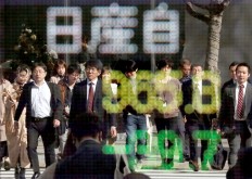 People are reflected in a stock quotation board showing the share price of the Nissan Motor Co. outside a brokerage in Tokyo on Tuesday. 