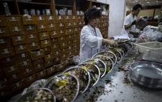 A woman mixing medicine in the pharmacy of the Yueyang Hospital, part of the Shanghai University of Traditional Chinese Medicine, in Shanghai on Nov. 7, 2018. 