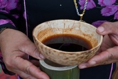This picture taken on November 28, 2018 shows an Indonesian woman holding a cup of Kawa Daun coffee served in a coconut shell during the Minangkabau arts and culture festival in Batusangkar, West Sumatra. The area is home to a peculiar take on the drink that extracts flavour from the plant's leaves rather than its beans. It is an old-fashioned brew dating back to the colonial period when few locals could afford bean-extracted coffee.