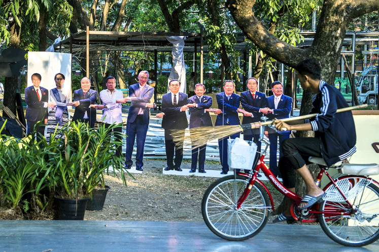 This photo taken on Sunday shows a worker cycling past life-size portraits of the 10 leaders of ASEAN as a government booth is dismantled following a cultural festival at Lumpini Park in Bangkok. Thailand will host the ASEAN summit in 2019.