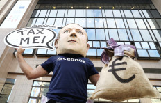 An activist wearing a mask depicting Facebook CEO Mark Zuckerberg demonstrates outside European Union headquarters in Brussels, Belgium, on Tuesday during the EU finance ministers’ meeting. France and Germany sought on Monday to salvage a proposed EU tax on big digital firms by narrowing the focus to cover only companies’ online advertising revenue.  
