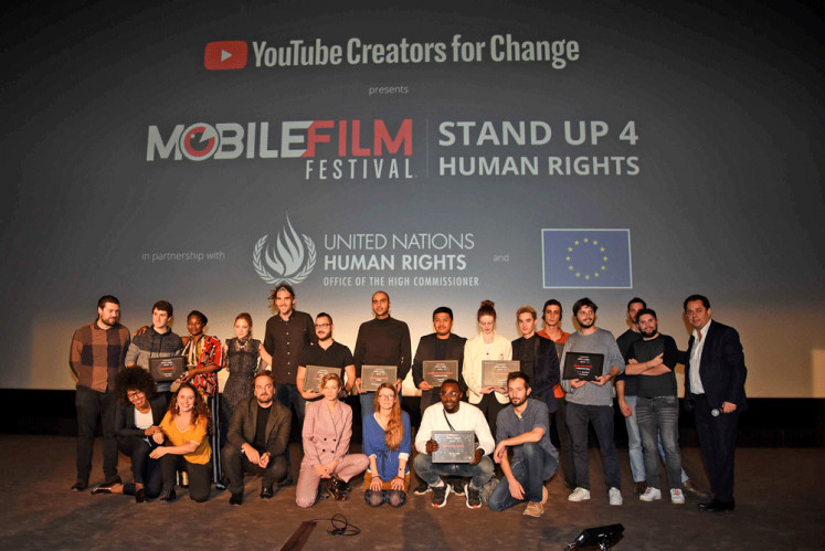 Creators for change: Mobile Film Festival founder Bruno Smadja (right, standing) strikes a pose with the winners and the judges at the festival’s award ceremony on Tuesday in Paris, France. 