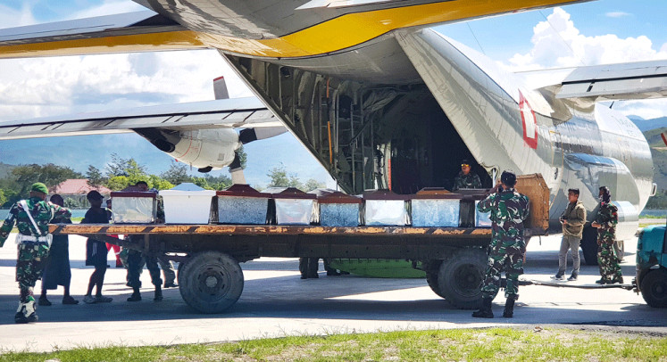 Time of loss: Indonesian Military officers load coffins into a carrier aircraft in Wamena, Papua, on Thursday. Indonesian security forces have retrieved the bodies of 16 people in the aftermath of a massacre of construction workers by separatist rebels in restive Papua province, the military said on Thursday.
