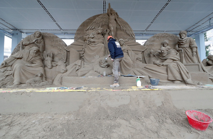 An artist works on a sand sculpture representing part of nativity scene in St. Peter's square at the Vatican, December 6, 2018.