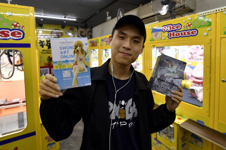 This picture taken on October 23, 2018 shows a university student holding prizes he won from a claw crane machine at a store in the Xizhi district in New Taipei City. As Taiwan's economy stagnates, claw crane arcades where customers lower a grabber to try to pick up a prize from a glass box are booming as affordable entertainment, while operators see them as a way to make a fast buck.