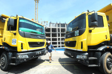A man walks between two dump trucks at a property construction project in Cikarang, West Java.