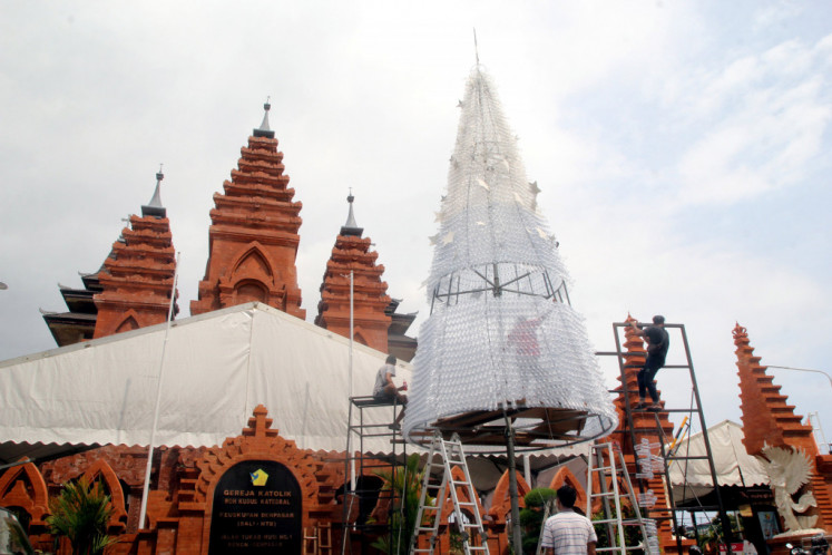 People prepare an 11-meter-high Christmas tree made of plastic bottles in front of Denpasar Cathedral in Bali, on Thursday, December 20, 2018. The tree is set to enliven Christmas celebrations and promote a campaign to reduce the use of plastics.