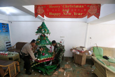 Sad Christmas: A police officer and a member of the military remove a Christmas tree from a tsunami-damaged building in the Carita Beach area, Pandeglang, Banten, on Monday, December 24, 2018. JP/Dhoni Setiawan