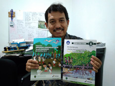 Guardian of nature: Hendra Gunawan, principal researcher at the Innovation, Research and Development Center in the Environment and Forestry Ministry’s office in Gunung Batu, Bogor, shows mangrove-themed school text books. 