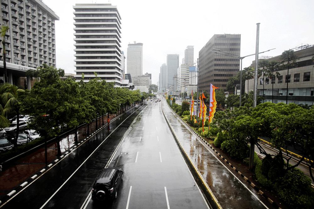 A vehicle passes a mostly empty and wet Jl. MH Thamrin in Central Jakarta on Jan. 1. Less traffic was reported on several main thoroughfares in the capital on the first day of 2019.