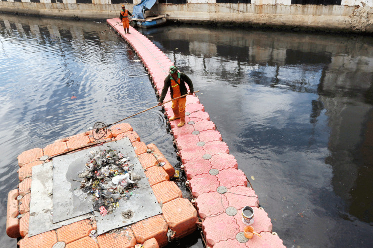 Workers remove trash from the Sentiong River, also known as Kali Item (Black River), on Thursday. Jakarta’s rivers are heavily polluted by solid and liquid waste because of a lack of waste treatment facilities and residents’ littering habit.