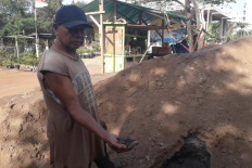A local resident holds soil from the soil mound behind him in Marunda, North Jakarta, on Jan. 4. It was found to contain hazardous and toxic (B3) waste that allegedly came from a local palm oil industry.