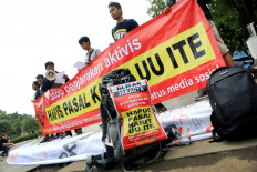 Activists stage a rally in front of the Presidential Palace in Jakarta on Tuesday, demanding the government abolish the Electronic Information and Transactions Law after an anticorruption activist in Blitar, East Java, was named a suspect of defamation for writing a Facebook post accusing a regent of corruption.